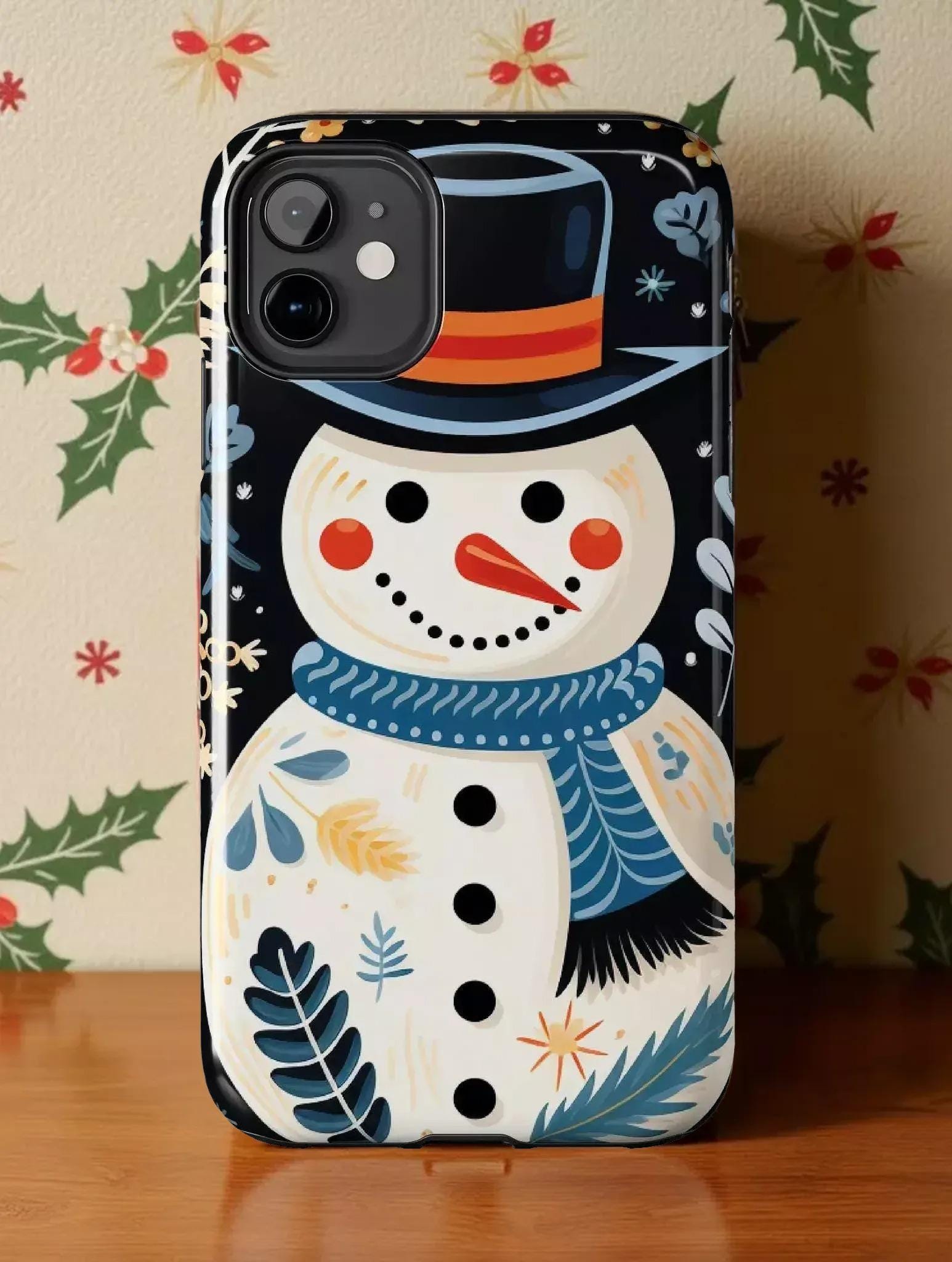 A colorful phone case featuring a snowman design with a black top hat, blue scarf, and various winter-themed elements.