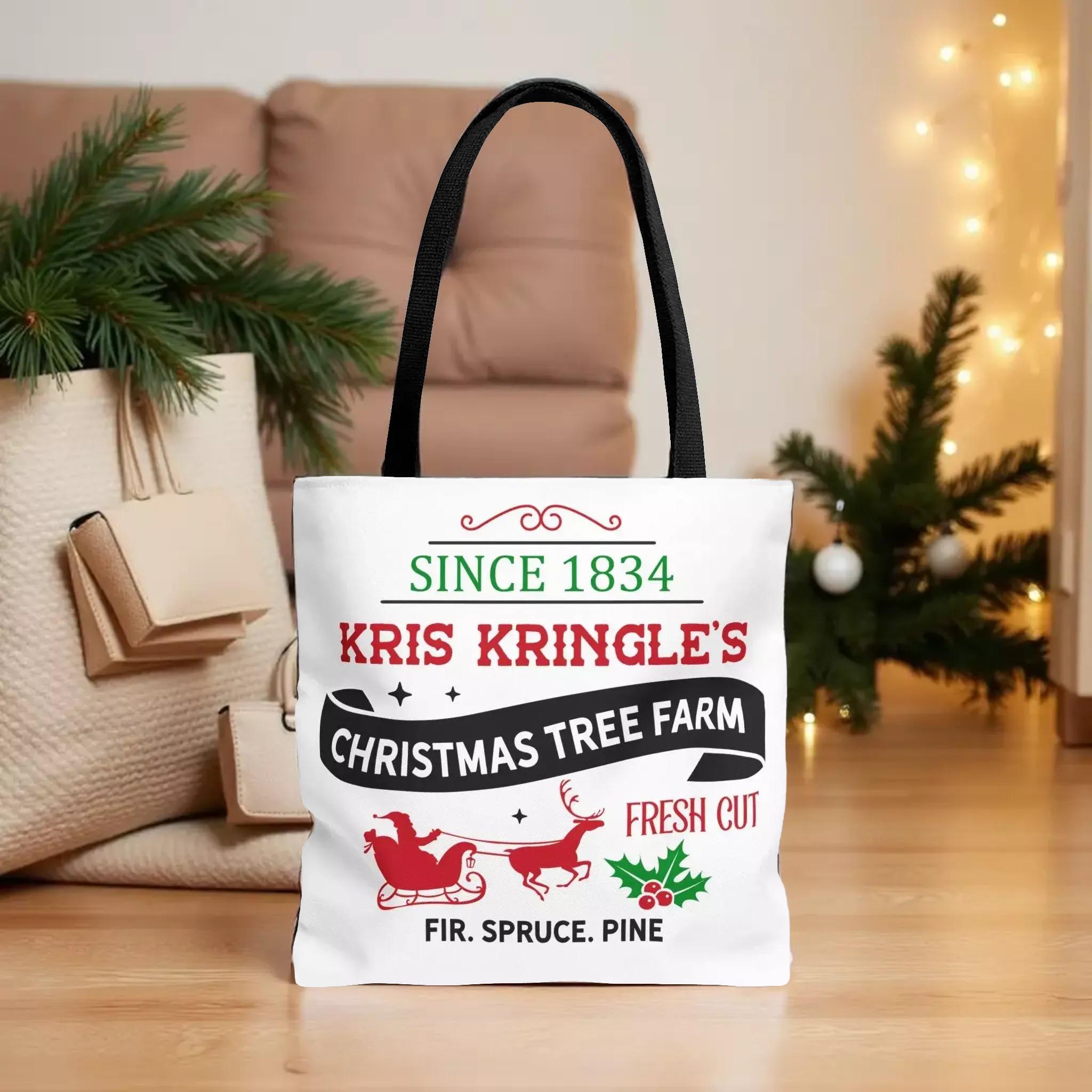 A white tote bag with text and graphics related to Kris Kringle's Christmas tree farm, placed on a wooden floor in front of a Christmas tree and other holiday decorations.