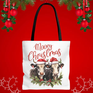 A white tote bag with a Christmas-themed design featuring two cows wearing Santa hats and surrounded by holly and berries.