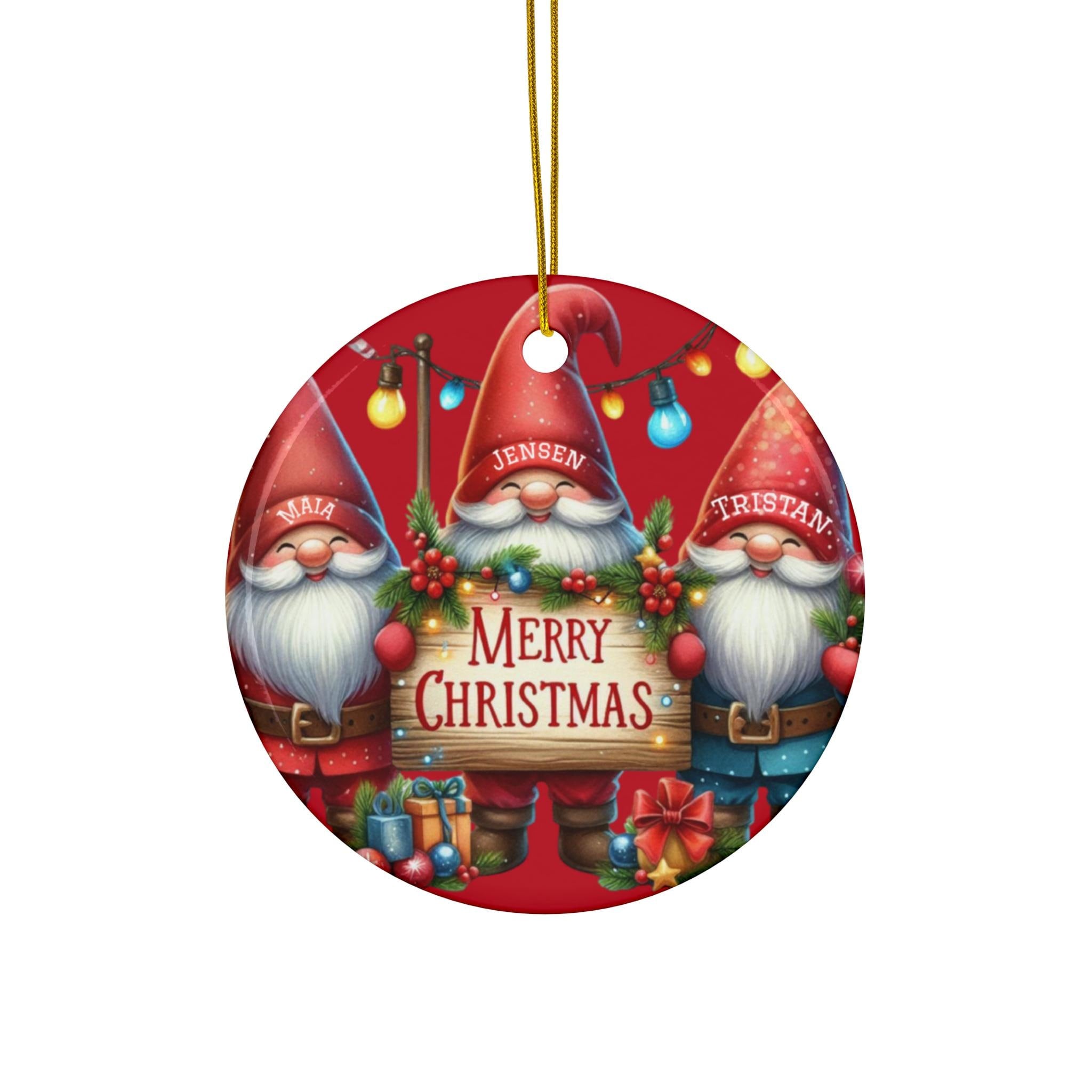 A red ornament with three smiling gnomes holding a sign that says "Merry Christmas".