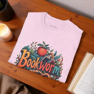 A pink t-shirt with a colorful graphic design featuring the word "Bookworm" surrounded by various elements such as leaves, an apple, and a book.