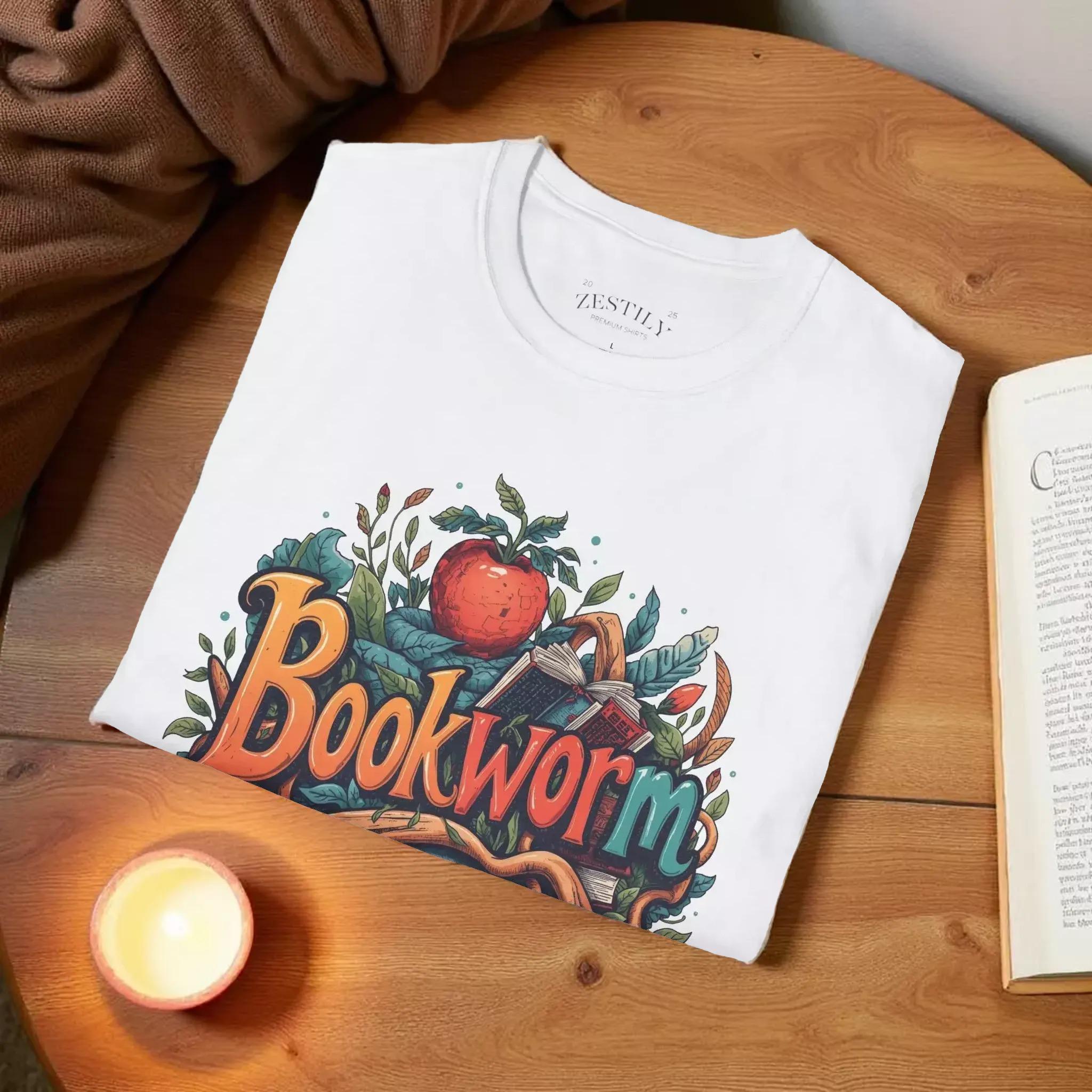 A white t-shirt with a colorful graphic design featuring the text "Book Worm" surrounded by various elements such as leaves, an apple, and a book.