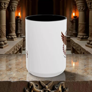 A white ceramic mug with a black interior and a graphic design featuring a bird and laurel wreath.