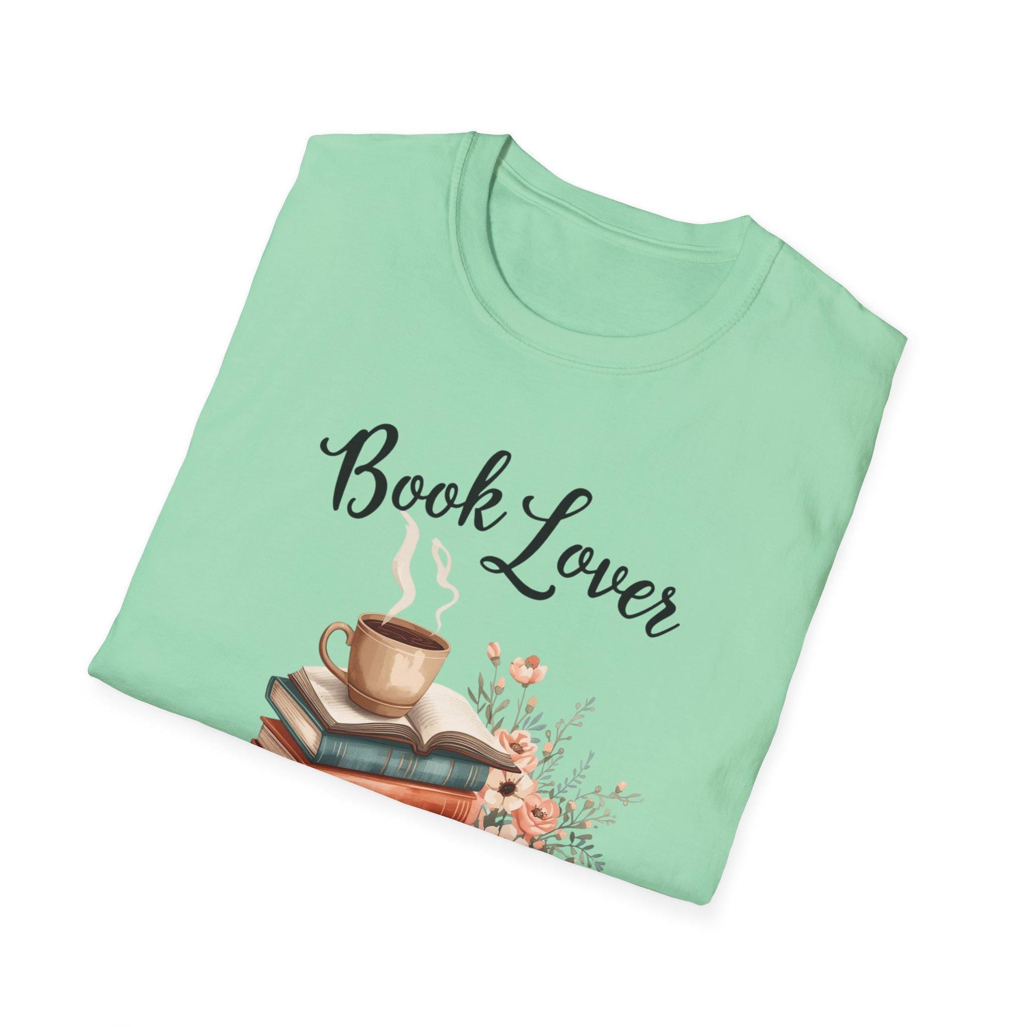 A green t-shirt with a printed design that includes a cup of coffee, a stack of books, and flowers. The text "Book Lover" is printed on the t-shirt.