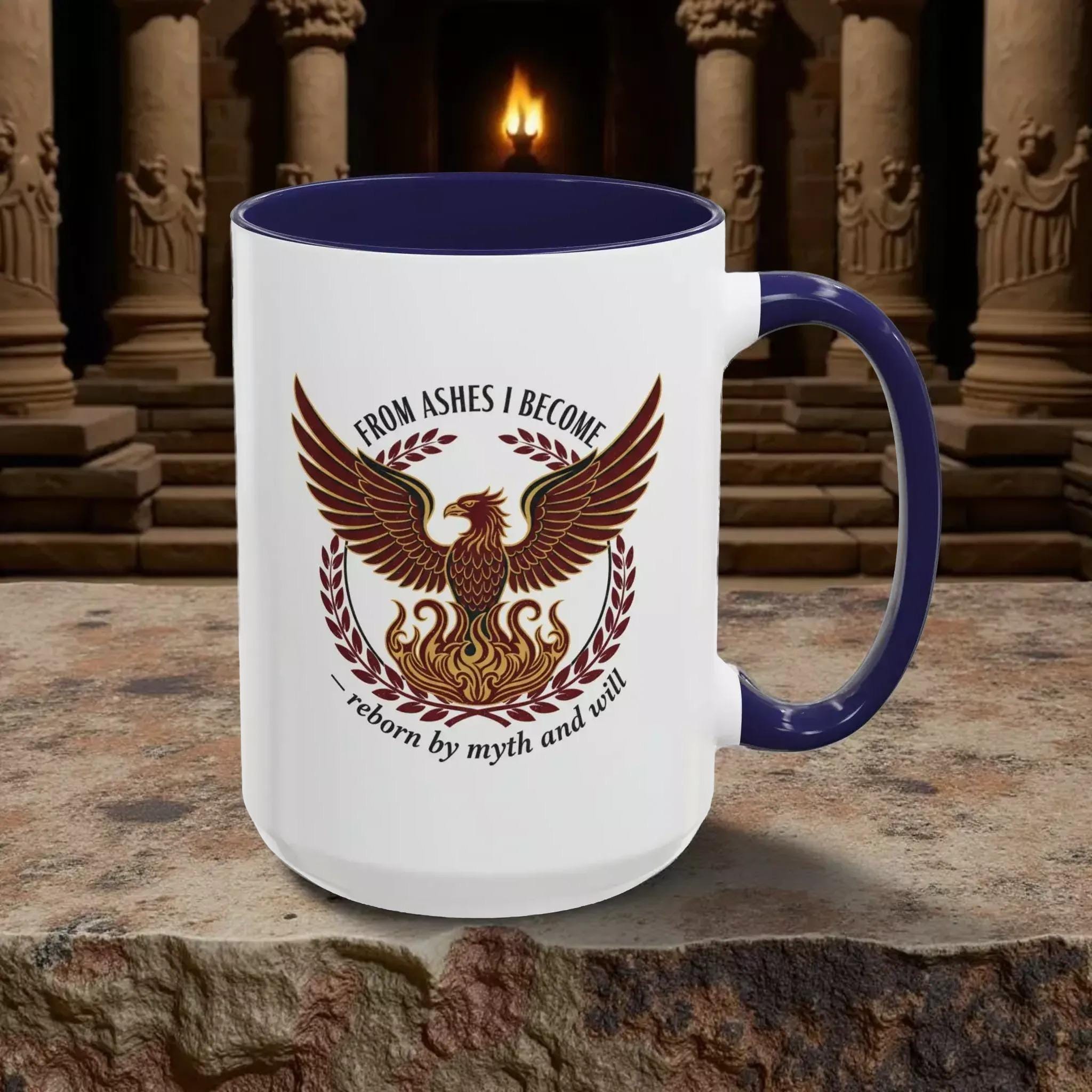 A white mug with a blue rim, featuring a graphic design of a phoenix with wings spread wide, surrounded by a laurel wreath.