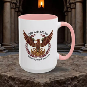 A white mug with a pink interior, featuring a graphic design of a phoenix with wings spread wide, surrounded by laurel branches and flames.