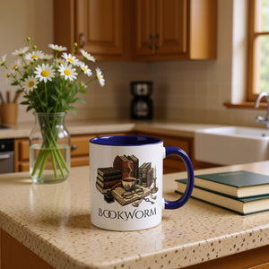 A white mug with a blue rim, featuring an illustration of a bookworm surrounded by various books, a cup of coffee, and other objects associated with reading and studying.