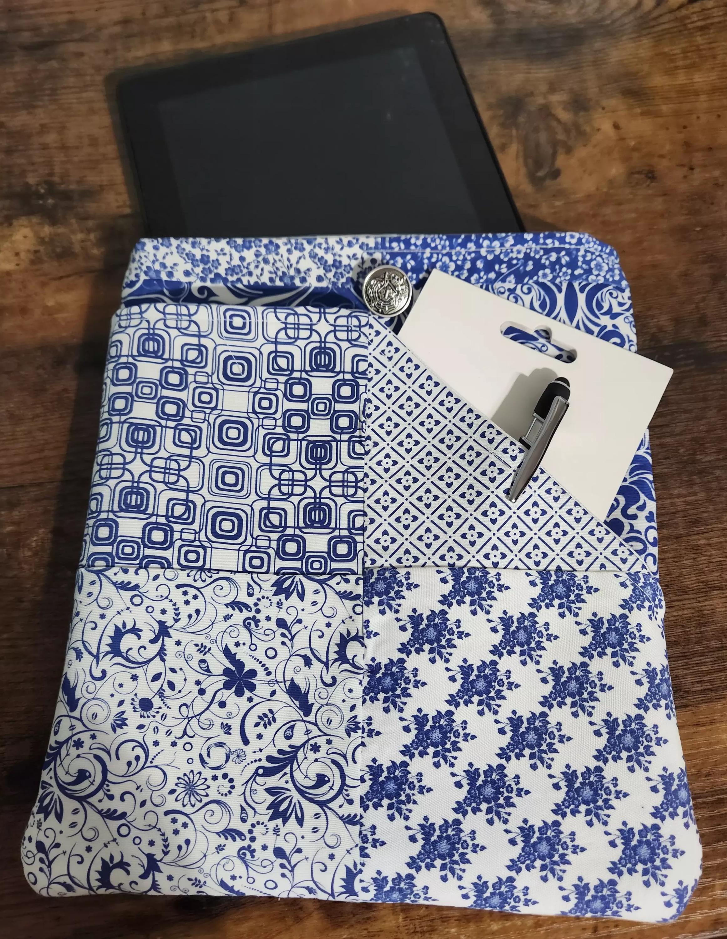 A wooden table with a tablet, pen, and paper, along with a patterned fabric, on top of it.