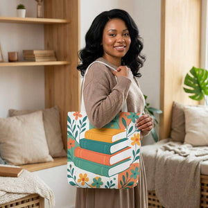 A woman with long, dark hair is standing in a room, holding a colorful tote bag with a book design on it.