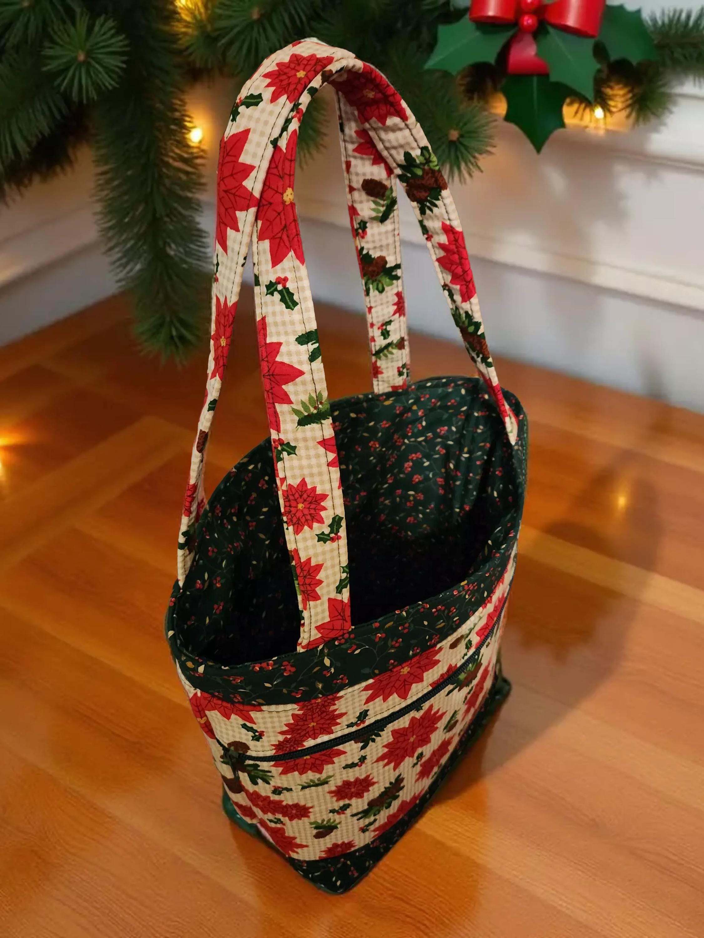 A hand-sewn tote bag with a floral pattern and red poinsettia flowers is displayed on a wooden floor, with a Christmas tree and holiday decorations visible in the background.