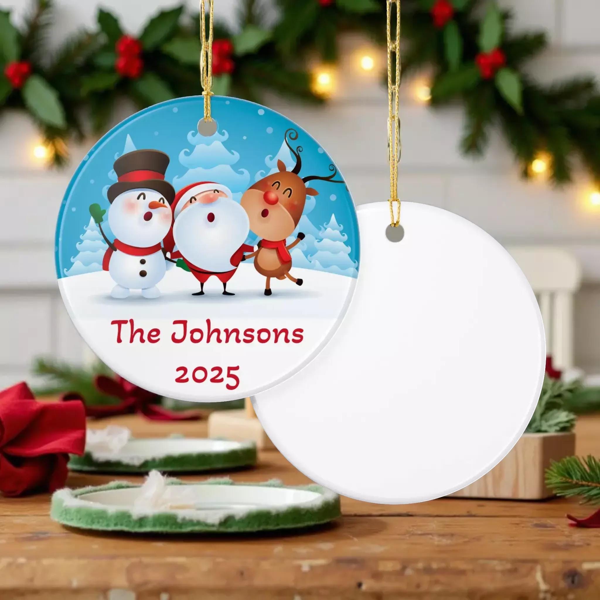 A Christmas ornament with Santa Claus, a reindeer, and a snowman, all wearing Santa hats and scarves, set against a snowy winter landscape. The ornament has the text "The Johnsons 2020" written on it.