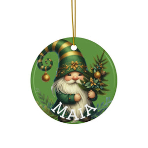 A round ornament featuring a gnome holding a Christmas tree and a gold bell.