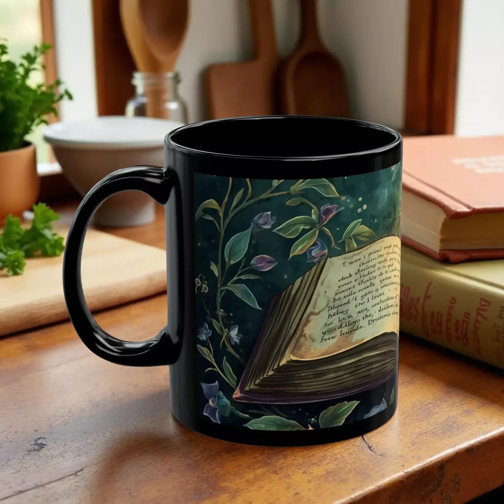 A black mug with an illustration of an open book surrounded by flowers and leaves on the cover.
