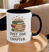 A white mug with a black handle, featuring a stack of colorful books and the text "Just one more chapter" printed on it.