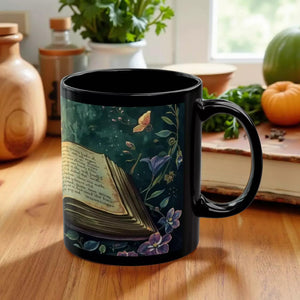 A black mug with an open book and colorful flowers printed on it.