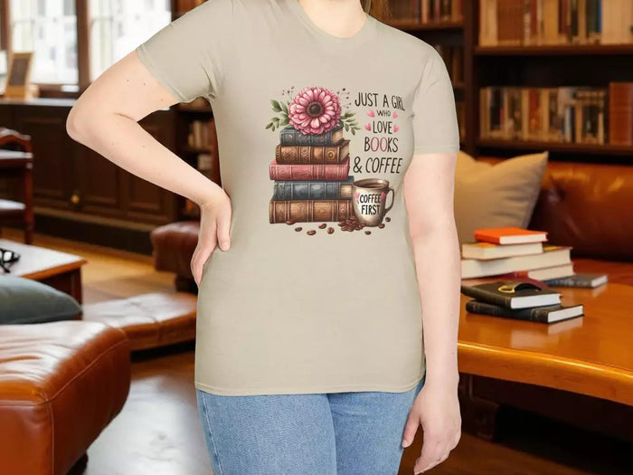 A smiling woman wearing a t-shirt with a graphic design of stacked books and coffee cups.