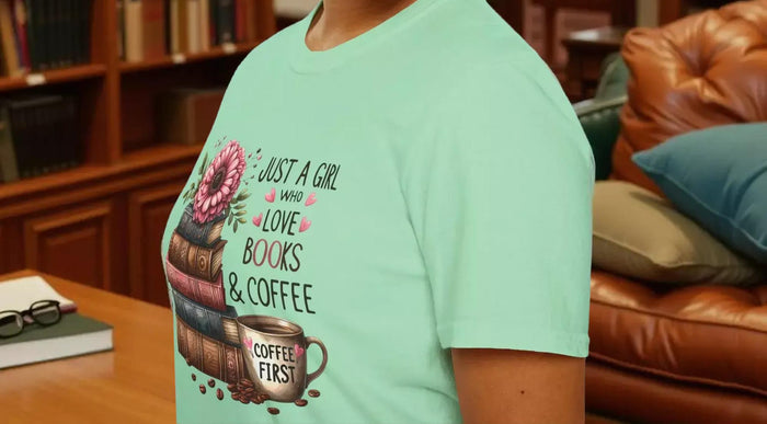 A smiling woman wearing a t-shirt with a graphic design of stacked books and coffee cups.