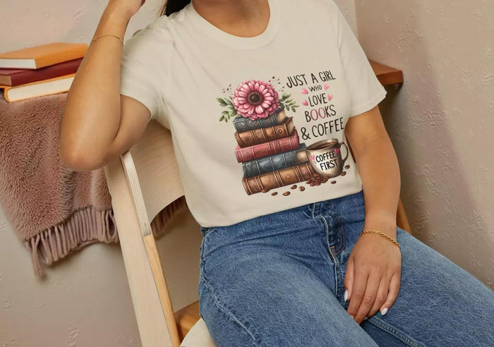 A smiling woman wearing a t-shirt with a graphic design of stacked books and coffee cups.