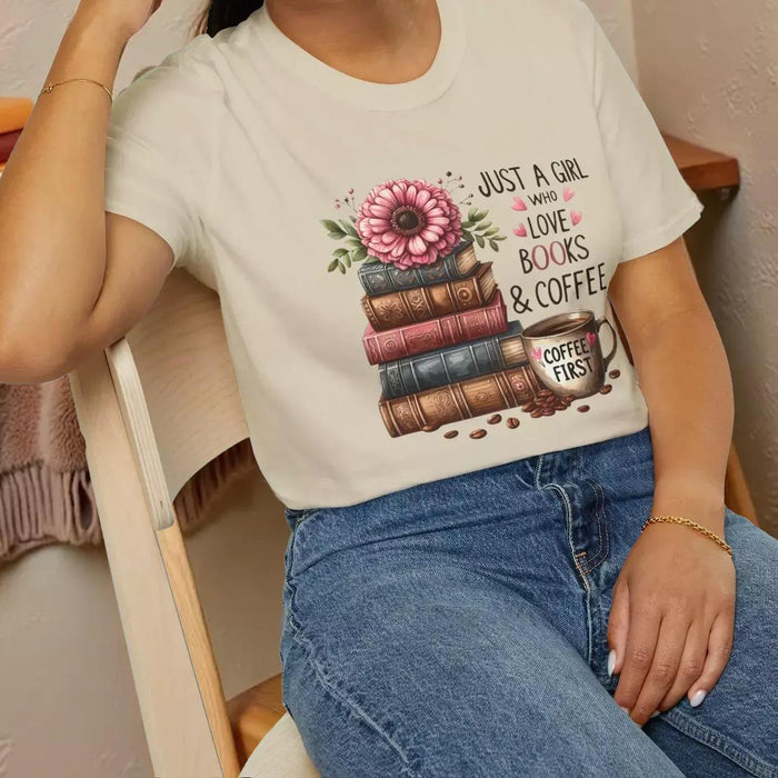 A smiling woman wearing a t-shirt with a graphic design of stacked books and coffee cups.