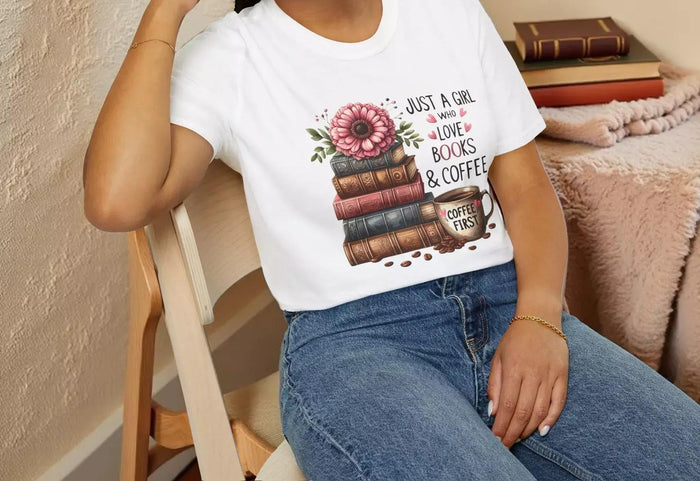 A smiling woman wearing a t-shirt with a graphic design of stacked books and coffee cups.