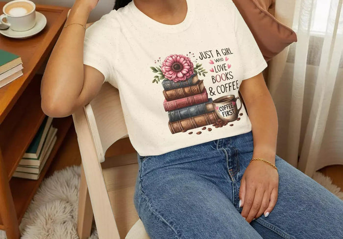 A smiling woman wearing a t-shirt with a graphic design of stacked books and coffee cups.