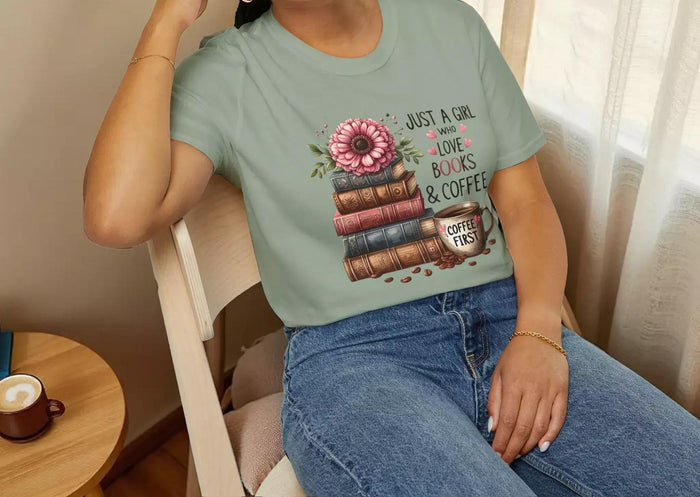 A smiling woman wearing a t-shirt with a graphic design of stacked books and coffee cups.