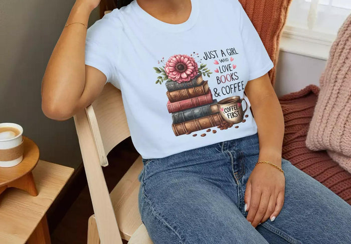 A smiling woman wearing a t-shirt with a graphic design of stacked books and coffee cups.
