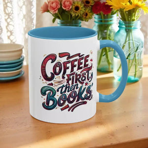 A white and blue mug with a blue handle, featuring a colorful and stylized text design that reads "Coffee first then books".