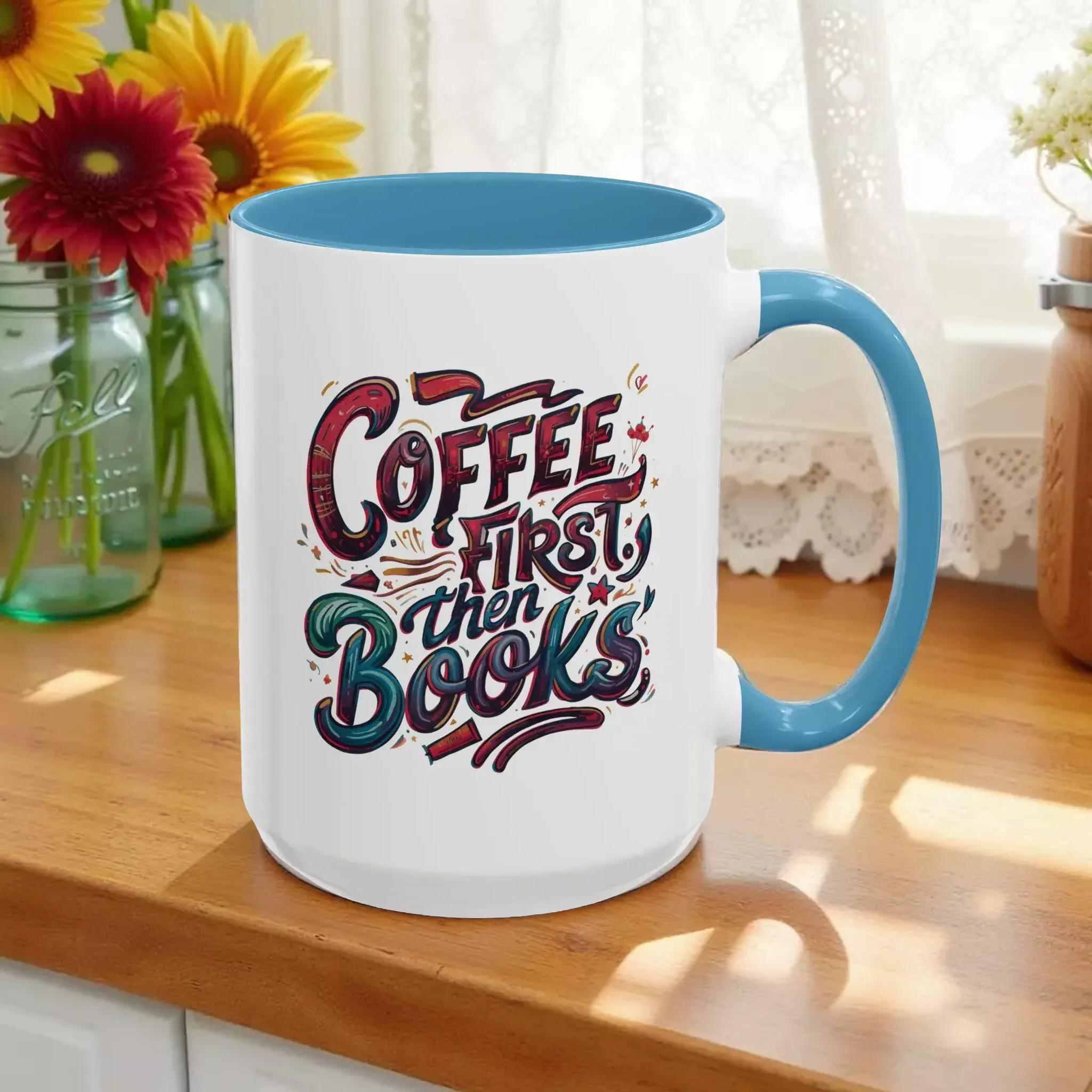 A white mug with a blue handle, featuring a colorful and artistic design with the text "Coffee first then books" printed on it.