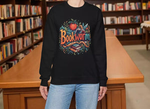 A woman wearing a black sweatshirt with a colorful graphic design featuring the text "Book worm" and an illustration of a book and an apple.