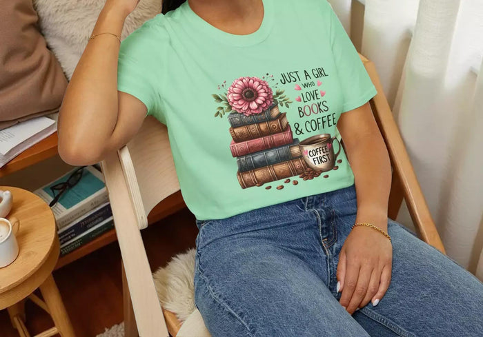 A smiling woman wearing a t-shirt with a graphic design of stacked books and coffee cups.