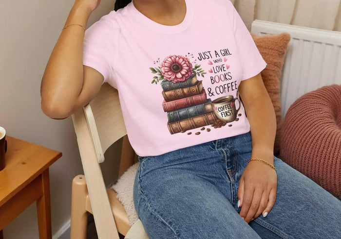 A smiling woman wearing a t-shirt with a graphic design of stacked books and coffee cups.