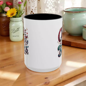 A white ceramic mug with a black interior, featuring colorful text and designs on its sides.