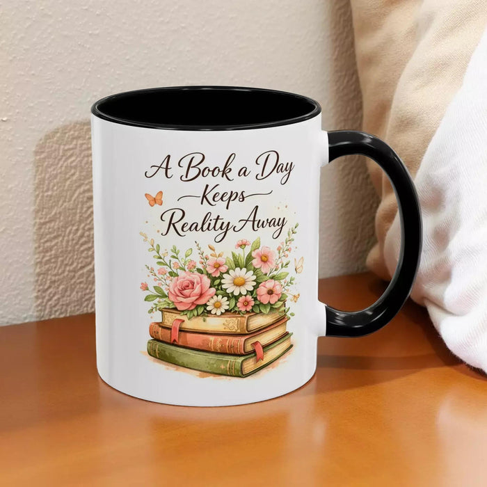 A white mug with a black handle, featuring a design of a stack of books with flowers on top.