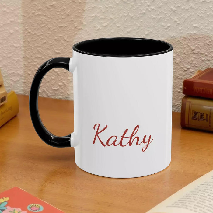 A white mug with a black handle, featuring a design of a stack of books with flowers on top.
