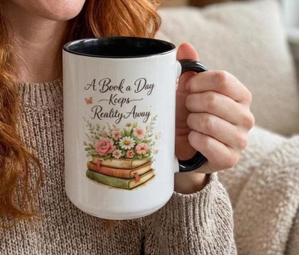 A white mug with a black handle, featuring a design of a stack of books with flowers on top.