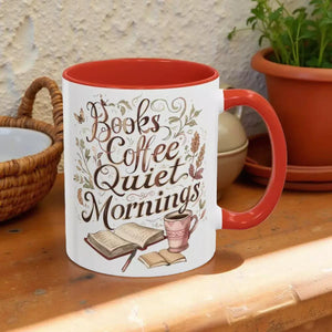 A white mug with a red handle, featuring a printed design that says "Books Coffee Quiet Mornings" along with illustrations of a book, a cup of coffee, and a warm beverage.