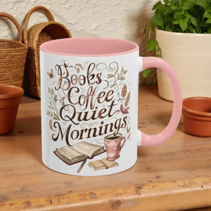 A white mug with a pink interior, featuring a design with the text "Books Coffee Quiet Mornings" and illustrations of a book, a cup of coffee, and a plant.