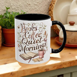 A white mug with a black handle, featuring a printed design that says "Books Coffee Quiet Mornings" along with illustrations of an open book, a cup of coffee, and a warm beverage.