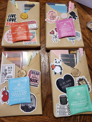 three wrapped packages with various stickers and labels on them, placed on a wooden surface.