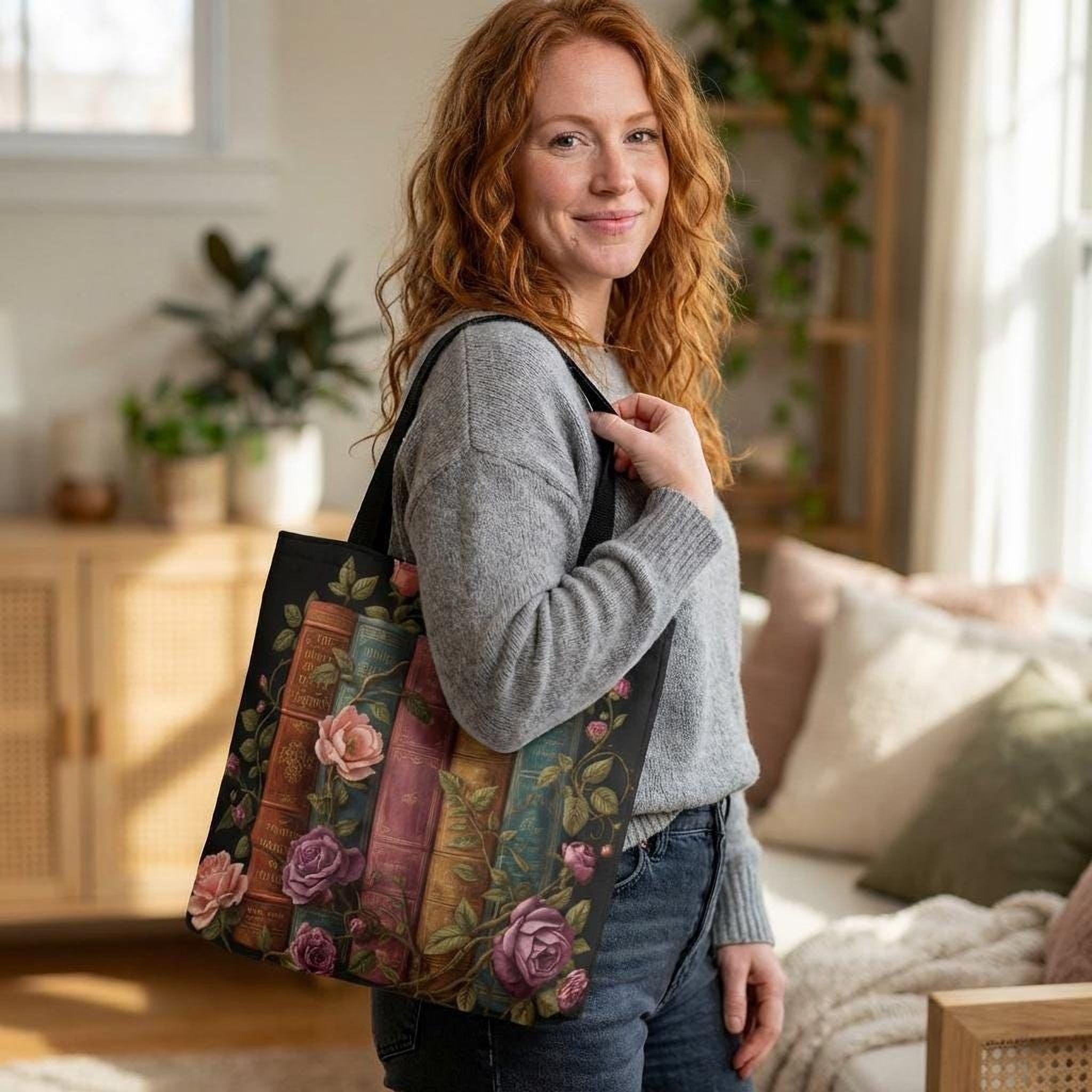 A woman with red hair is standing in a room, holding a tote bag with a floral design on it.