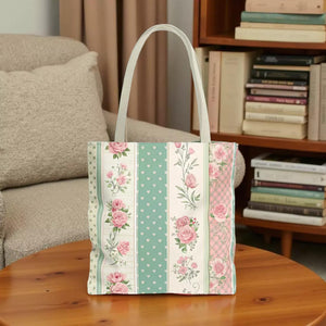 A tote bag with a floral pattern in shades of pink, green, and white. The pattern consists of vertical stripes with pink roses and green leaves, as well as polka dots and floral designs.