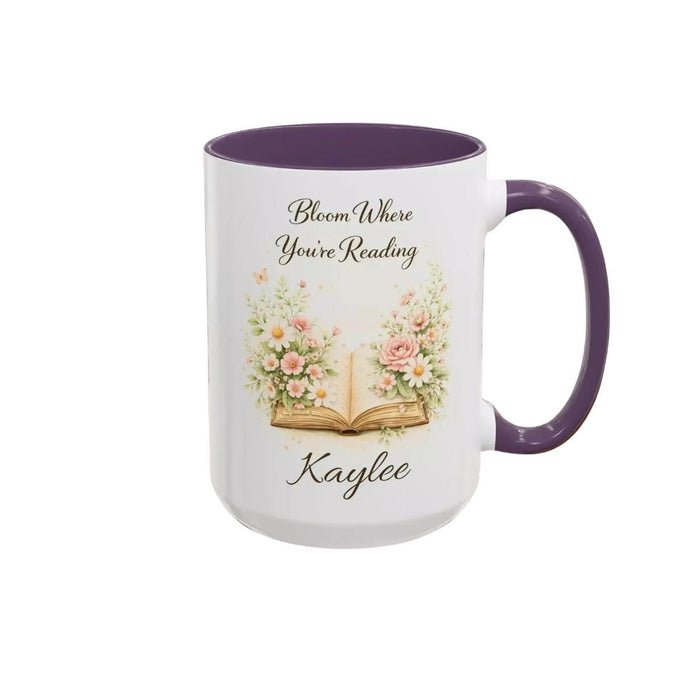 A white mug with a blue handle, featuring an illustration of an open book surrounded by flowers.