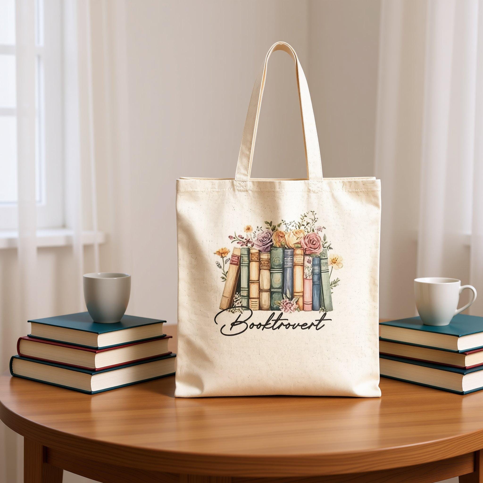 A beige tote bag with a printed design of a row of colorful books surrounded by flowers.