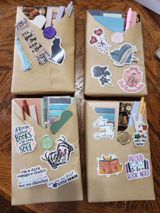 two wrapped books with red ribbons, along with various items such as tea bags, a mug, and a scroll. The text overlay reads "Blind Date with a Book" and "BONUS Extras".