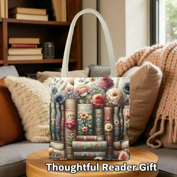A tote bag with a floral pattern and a mug with a book and flower design, both placed on a stack of books.