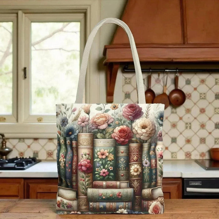 A tote bag with a floral pattern and a mug with a book and flower design, both placed on a stack of books.