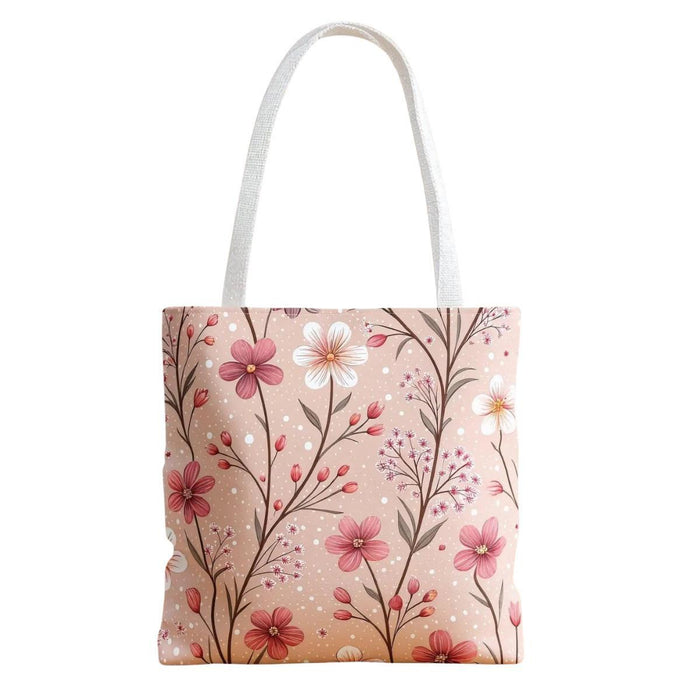 A tote bag with a floral pattern and a travel mug are displayed on a table, along with a book and some rose petals.