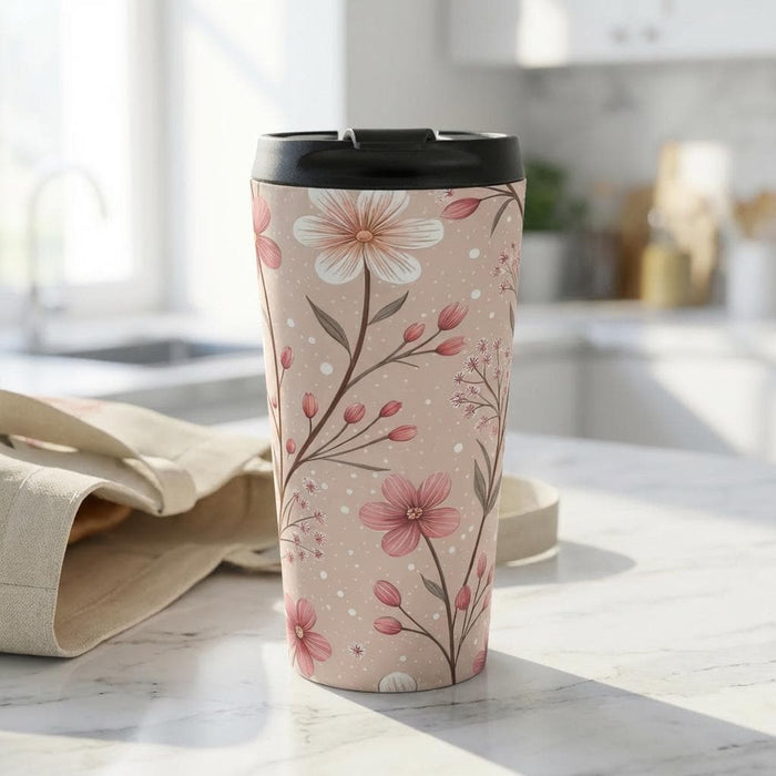 A tote bag with a floral pattern and a travel mug are displayed on a table, along with a book and some rose petals.