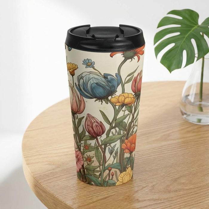 A tote bag with a floral pattern and a matching travel mug are displayed on a bed with white sheets and flowers.
